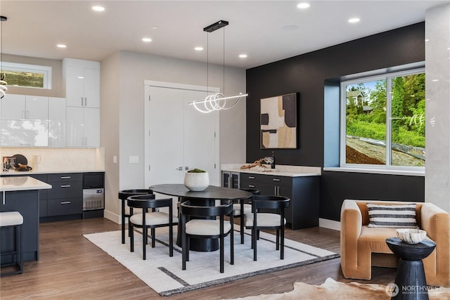 dining room with recessed lighting, wood finished floors, baseboards, and bar area
