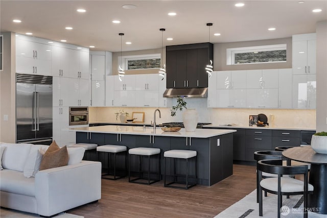 kitchen featuring stainless steel appliances, modern cabinets, dark wood-type flooring, light countertops, and recessed lighting