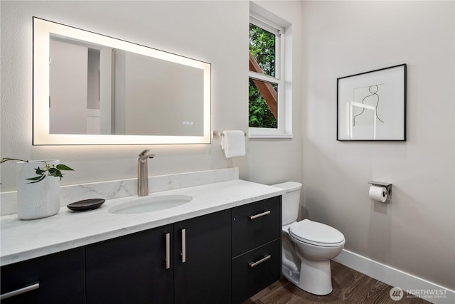 bathroom with wood finished floors, toilet, vanity, and baseboards