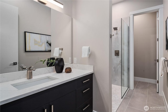 bathroom with a stall shower, vanity, tile patterned flooring, and baseboards