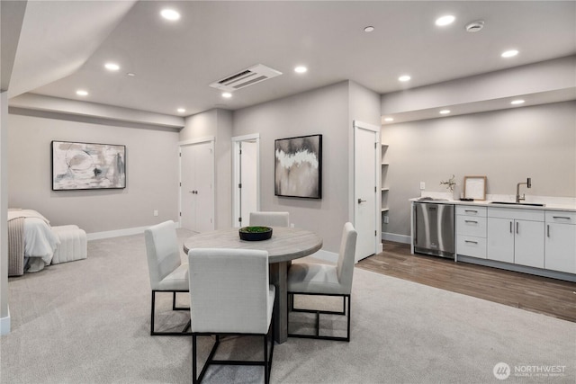 carpeted dining area with baseboards, recessed lighting, and bar with sink