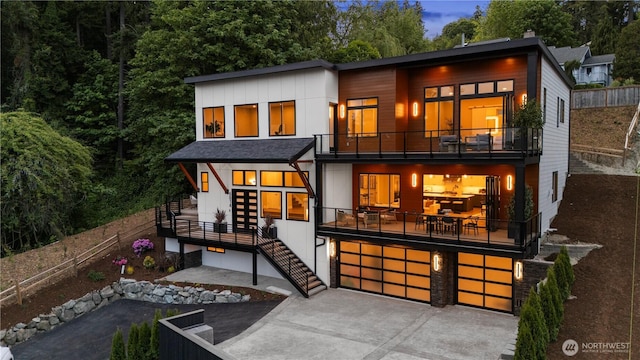 back of property with a balcony, stairs, an attached garage, and concrete driveway