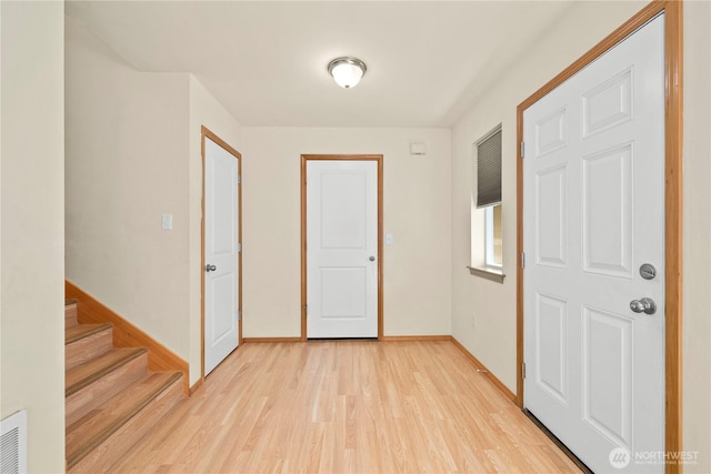 foyer featuring light wood finished floors, baseboards, and stairs