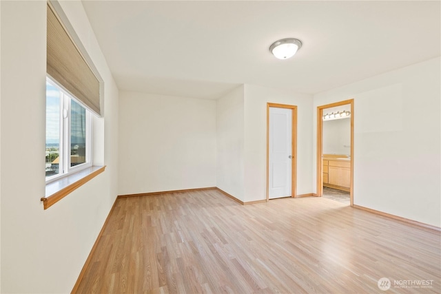 spare room featuring light wood finished floors and baseboards