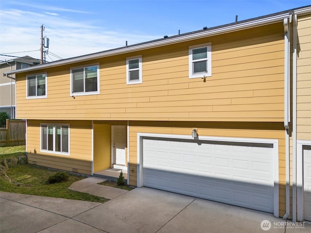 view of front facade featuring an attached garage, driveway, and fence