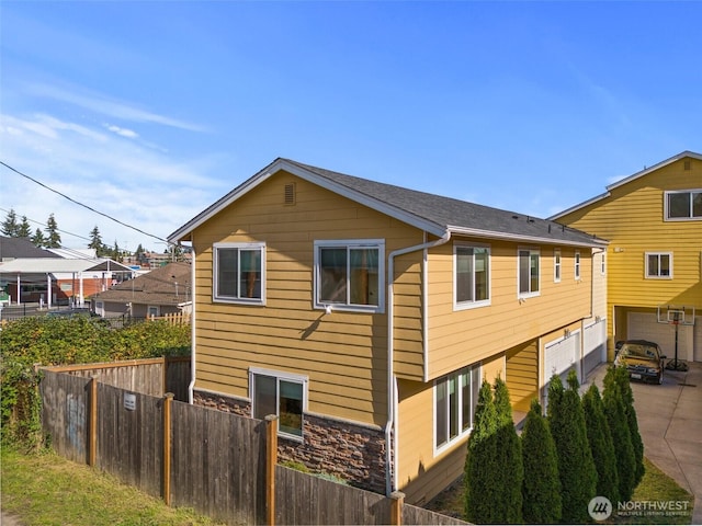 view of side of home with fence and stone siding