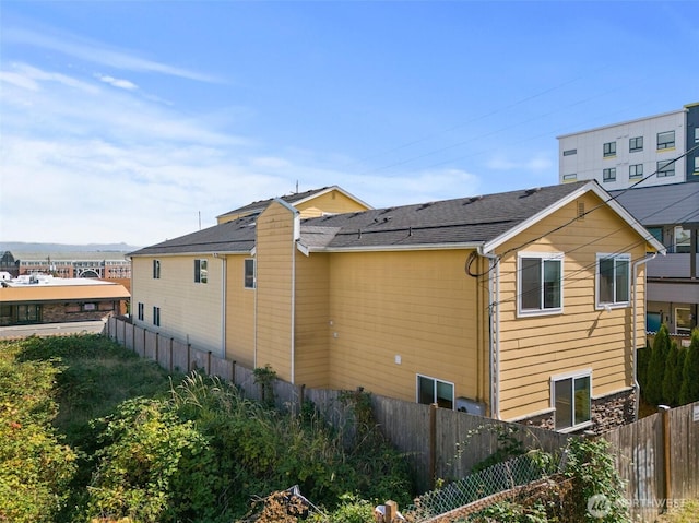 view of property exterior featuring fence and roof with shingles