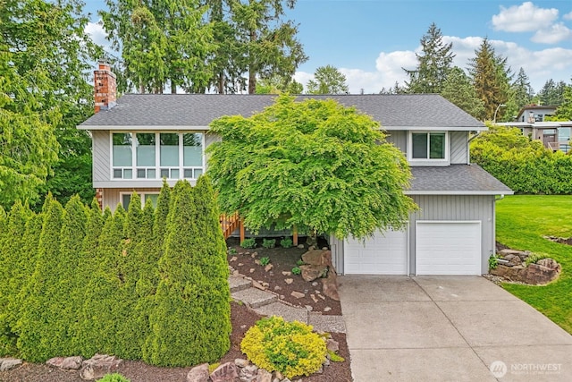 view of front of property featuring an attached garage, roof with shingles, a chimney, concrete driveway, and a front lawn
