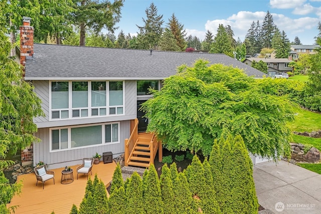 view of front of house featuring a wooden deck, a shingled roof, stairs, and a chimney