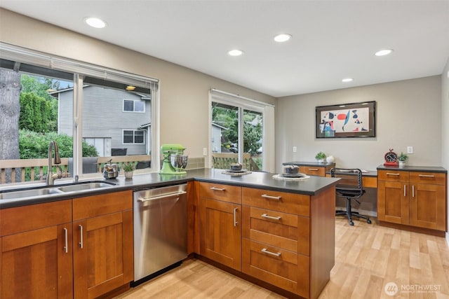 kitchen with stainless steel dishwasher, a sink, light wood-style flooring, recessed lighting, and dark countertops