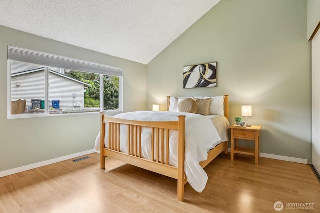 bedroom with wood finished floors, baseboards, and high vaulted ceiling