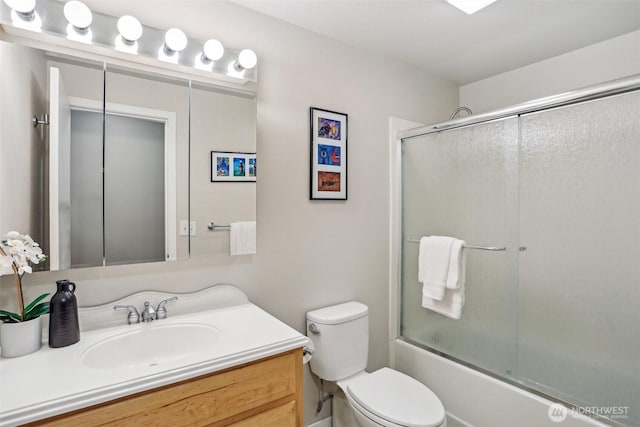 bathroom with toilet, vanity, and combined bath / shower with glass door