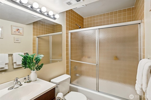 full bath featuring combined bath / shower with glass door, vanity, and toilet
