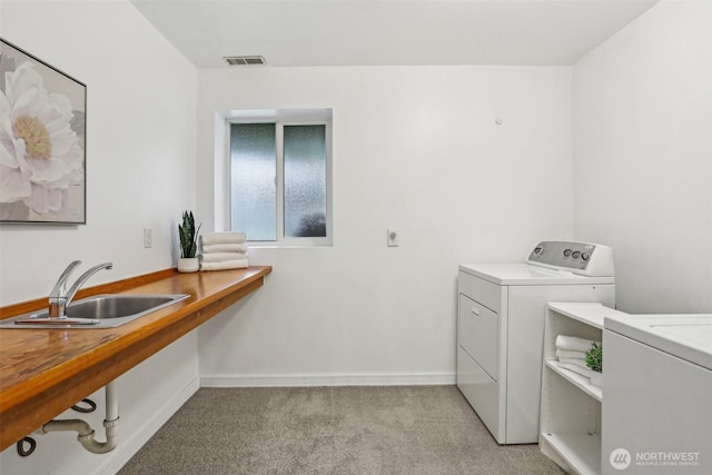 laundry room with light colored carpet, washing machine and clothes dryer, and baseboards
