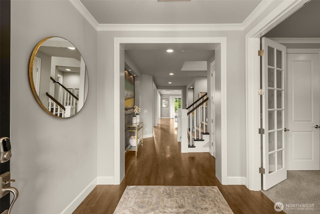 hall with stairs, wood finished floors, baseboards, and ornamental molding
