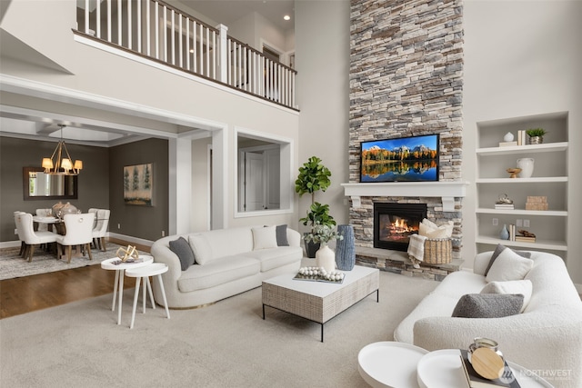 living room with a chandelier, a fireplace, carpet flooring, a high ceiling, and baseboards