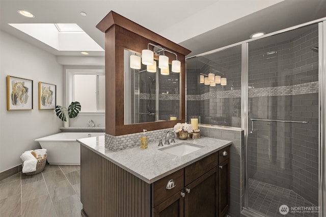 full bathroom with a shower stall, recessed lighting, vanity, a freestanding bath, and a skylight