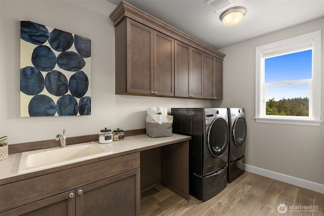 laundry room featuring independent washer and dryer, cabinet space, light wood-style flooring, and baseboards
