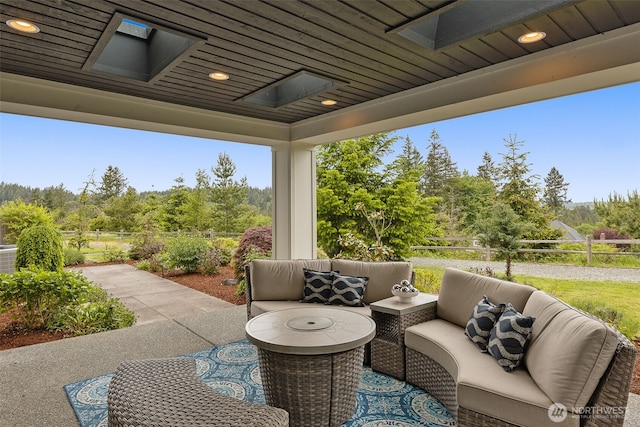 view of patio / terrace with an outdoor hangout area, fence, and view of wooded area