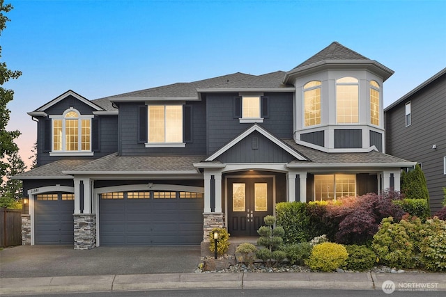 view of front facade featuring an attached garage, roof with shingles, driveway, and stone siding