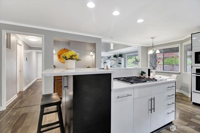 2711 NE 4th Ct, Renton, WA 98056 - kitchen with stainless steel gas cooktop, dark wood-style floors, crown molding, a kitchen island, and light countertops
