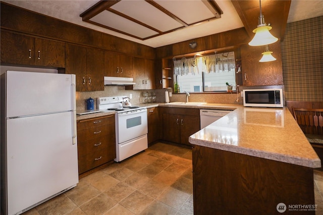 kitchen featuring white appliances, under cabinet range hood, a sink, and light countertops