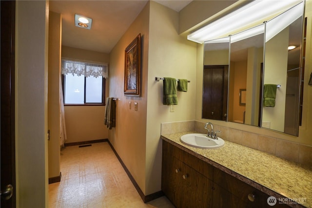 bathroom featuring vanity, baseboards, tile patterned floors, and decorative backsplash