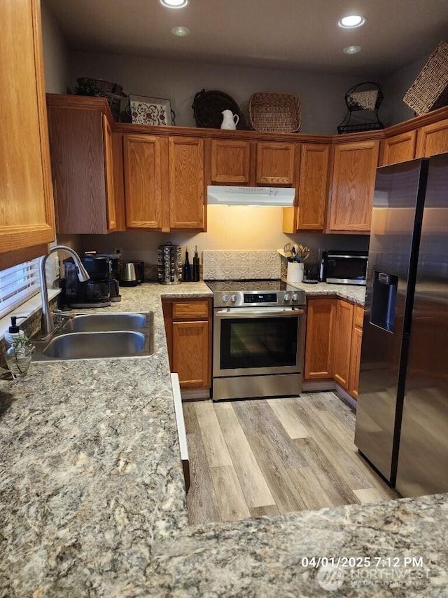 13816 NE 63rd St, Vancouver, WA 98682 - kitchen featuring stainless steel appliances, under cabinet range hood, a sink, light wood-style floors, and brown cabinets