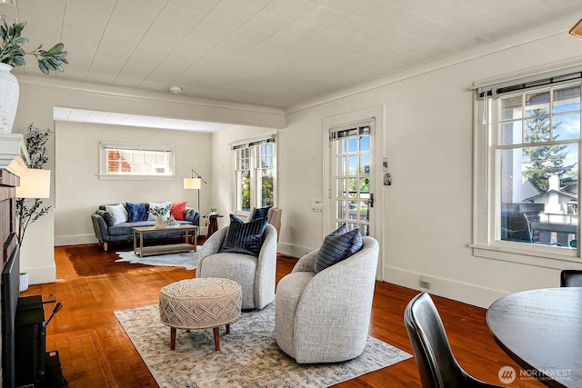 living area featuring plenty of natural light, crown molding, wood finished floors, and baseboards