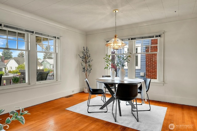 dining room with light wood-style floors, a chandelier, and baseboards