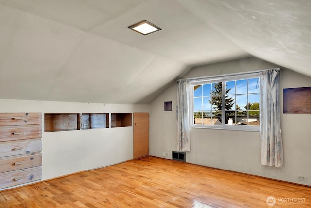 bonus room with light wood-style flooring and vaulted ceiling