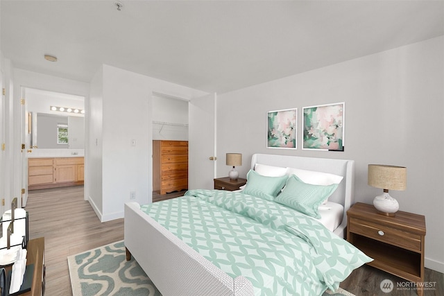 bedroom featuring light wood-type flooring, baseboards, ensuite bath, and a closet