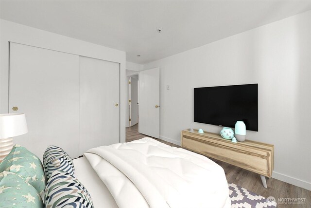 bedroom featuring wood finished floors, baseboards, and a closet