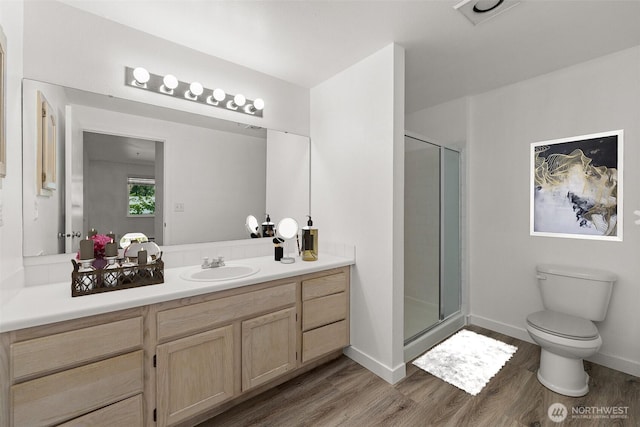 full bathroom with toilet, a shower stall, wood finished floors, vanity, and baseboards