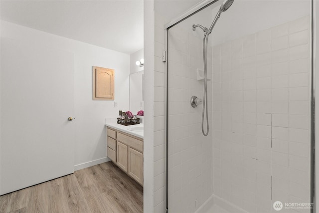 bathroom with wood finished floors, vanity, and a tile shower