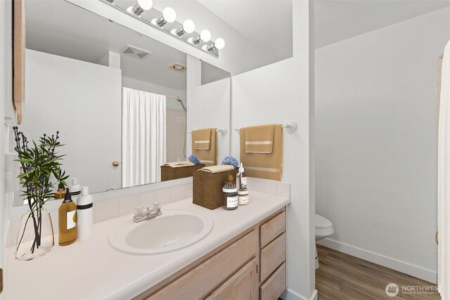 full bathroom featuring toilet, wood finished floors, a shower with curtain, vanity, and baseboards