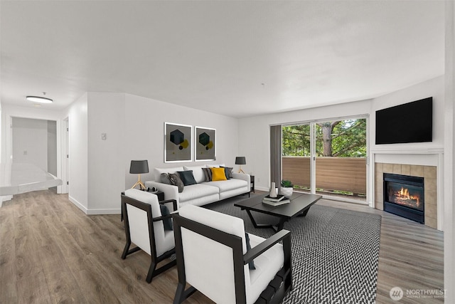 living room featuring wood finished floors, baseboards, and a tile fireplace