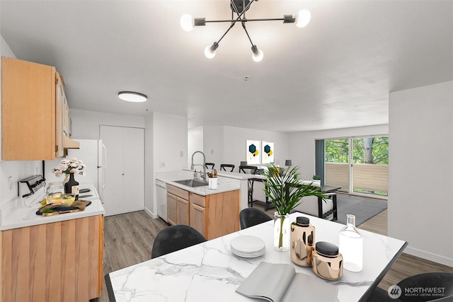 kitchen featuring a sink, white appliances, light countertops, light wood-type flooring, and baseboards