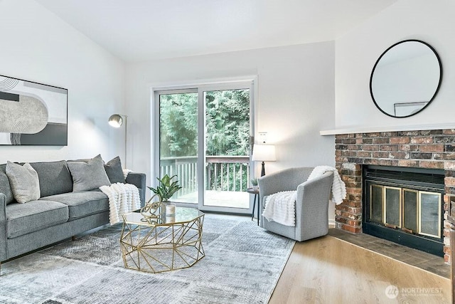 living room with wood finished floors and a brick fireplace