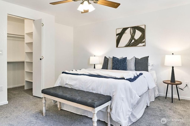 bedroom with carpet flooring, a walk in closet, baseboards, and a ceiling fan