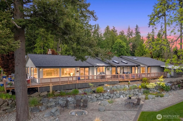 15208 W Lake Goodwin Rd, Stanwood, WA 98292 - back of house at dusk featuring a deck, a patio area, a chimney, and roof with shingles
