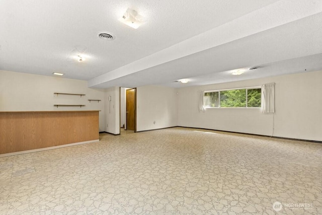 unfurnished living room with baseboards and a textured ceiling
