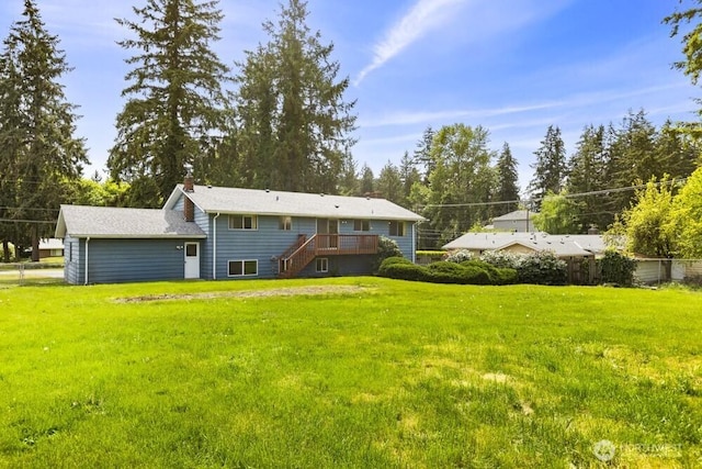 back of property featuring stairway, a yard, a chimney, and a wooden deck