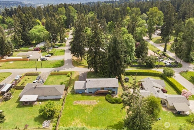 aerial view of property and surrounding area featuring a heavily wooded area and nearby suburban area