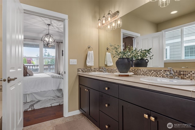13708 Big Sky Dr E, Bonney Lake, WA 98391 - full bathroom featuring a chandelier, ensuite bath, double vanity, backsplash, and wood finished floors
