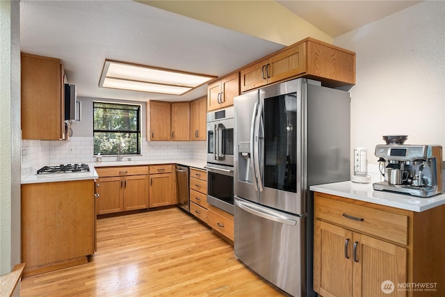 3912 Sutherland St, Gig Harbor, WA 98332 - kitchen featuring appliances with stainless steel finishes, light wood finished floors, tasteful backsplash, and light countertops