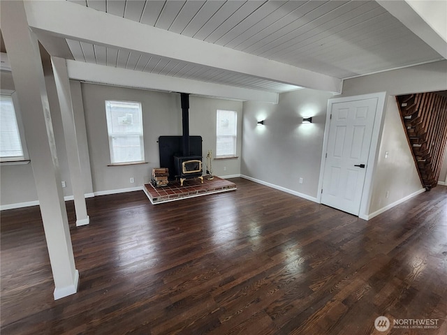 unfurnished living room with stairs, baseboards, wood finished floors, and beam ceiling