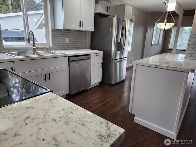 kitchen featuring appliances with stainless steel finishes, a sink, dark wood-style flooring, decorative backsplash, and white cabinetry
