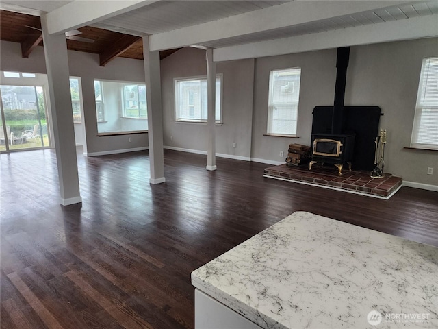living room featuring baseboards, a wood stove, and dark wood-style flooring