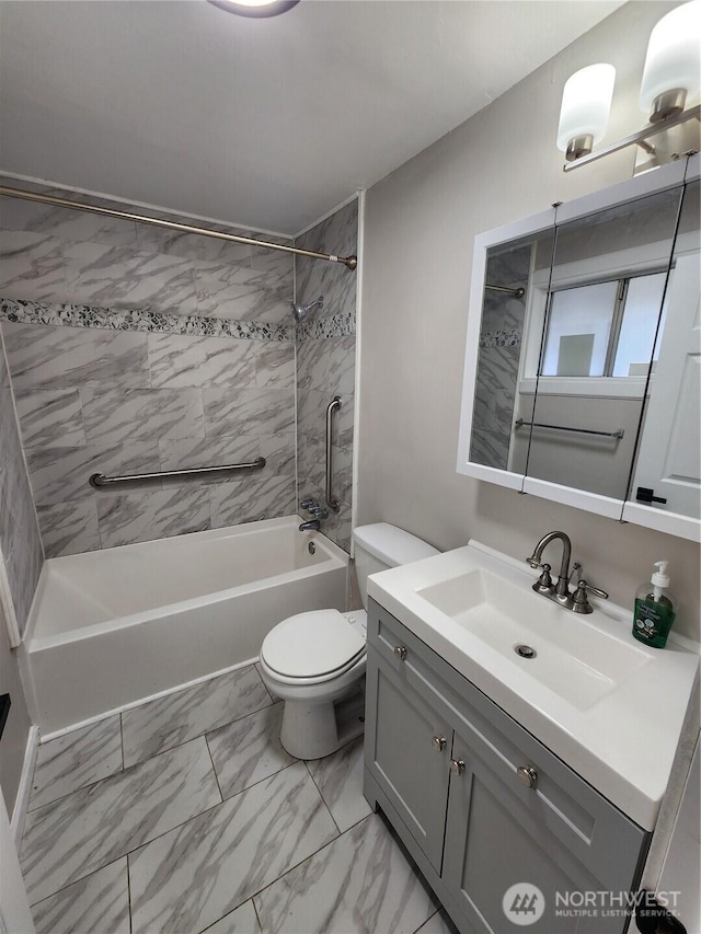 bathroom featuring marble look tiles, toilet,  shower combination, and vanity